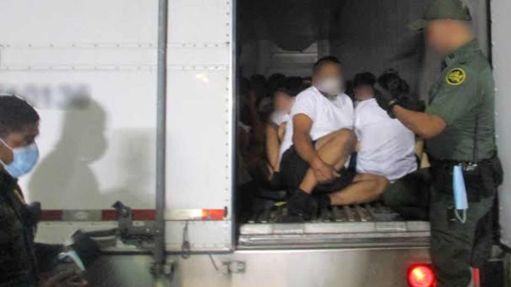 Humans being transferred at the back of a truck 